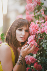 Woman beauty with tattoo on hand near roses in garden.