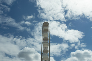 Ferris wheel on the blue cloudy sky. Background concept of happy holidays time.