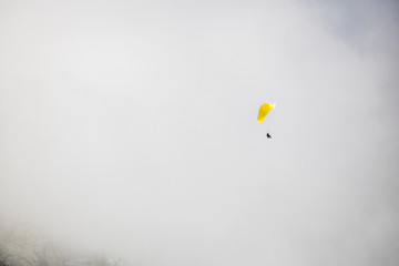 Paraglider floating through clouds over Camps Bay, Cape Town.