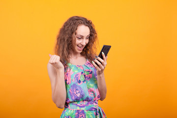 Naklejka premium Young woman looking with excitement at her phone