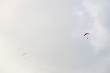 Two paragliders floating through clouds over Camps Bay, Cape Town.
