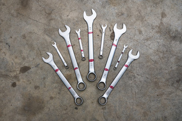 Several small and big sizes wrenches lying on concrete floor in shape of crown.