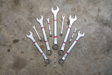 Set of different sizes wrenches lying on concrete floor in shape of crown.