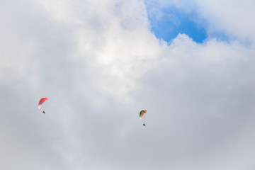 Paragliders floating through clouds and blue sky over Camps Bay, Cape Town.