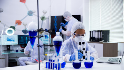 Female scientist in protection equipment adjusting her microscope