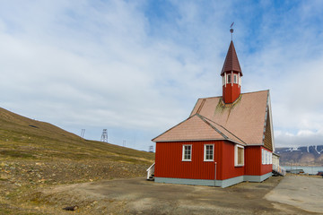 Fototapeta premium red Svalbard church in Longyearbyen, cloudy blue sky, sunlight