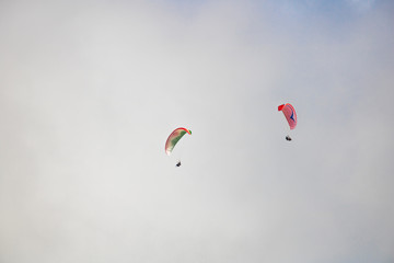 Two paragliders floating through clouds over Camps Bay, Cape Town.