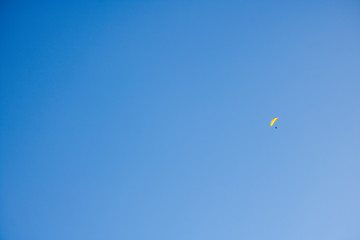 Paragliders floating through a blue sky over Camps Bay, Cape Town.