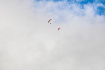 Two paragliders floating through clouds over Camps Bay, Cape Town.