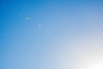 Paraglider floating through a blue sky over Camps Bay, Cape Town.
