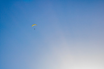 Paraglider floating through a blue sky over Camps Bay, Cape Town.