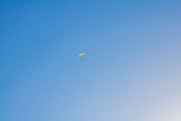 Paraglider floating through a blue sky over Camps Bay, Cape Town.