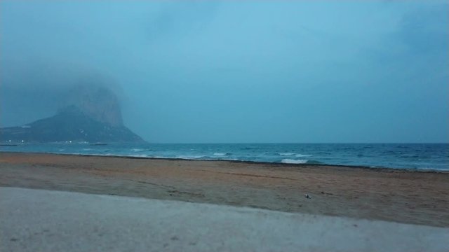 Beautiful view of Penyal d'Ifac at blue hour and Calp beach with mediterranean sea on a calm spring evening