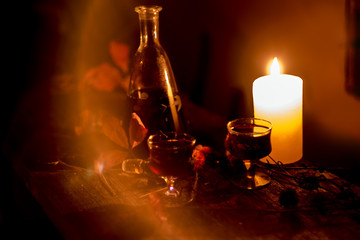 Cozy evening still life by . A glass of red wine, an old decanter, green leaves and dried flowers...