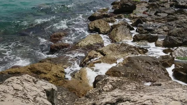 Mediterranean sea waves hitting the rocks on a sunny day