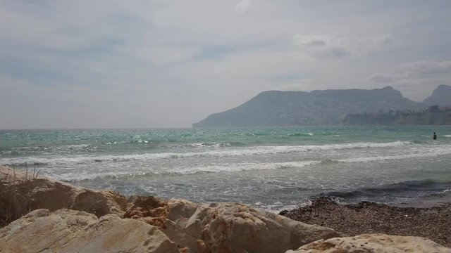 Man entering the wavy mediterranean sea at Costa Blanca on a sunny day