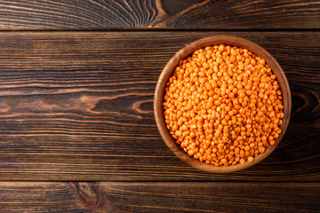 Red lentil on dark wooden background.