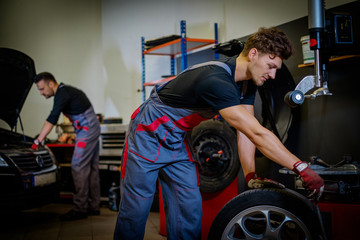 Fototapeta na wymiar Car mechanic mounts tire on wheel in a workshop