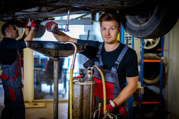 Fototapeta na wymiar Car mechanic changes oil in a workshop