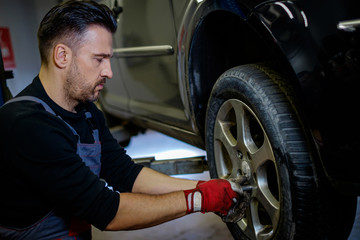 Car mechanic replacing wheel in a workshop