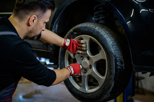 Car mechanic replacing wheel in a workshop
