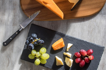 Cheese selection served with red white and black grapes. Flatlay snack food image.