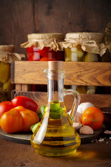Glass bottle with oil on the background of glass jars with homemade pickled vegetables