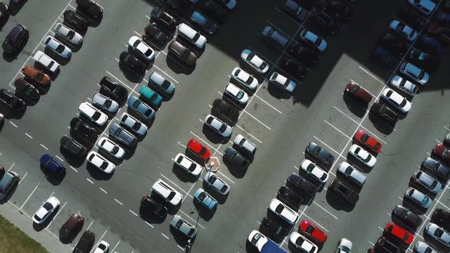 A view from above to the process of car parking. Heavy traffic in the parking lot. Searching for spaces in the busy car park. Parking advice. Cruising for parking in busy business center