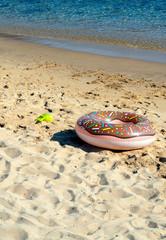 Greece, Ios, the Cyclades. A lone blown up water ring at the waters edge at the beach of Mylopotos. Fine sand, a sunny day, relaxation and holiday fun. Simple pleasures at the seaside.