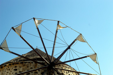 Obraz premium Greece, the isle of Santorini. A lone windmill. The white sails contrast with the deep blue summer sky. Tradition and nature. A proud and simple building that has stood the test of time.