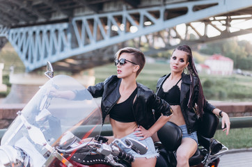 Naklejka premium Sexy gorgeous young women outdoors with motorcycle on road. Friendship, beauty, sexy lady, transportation concept