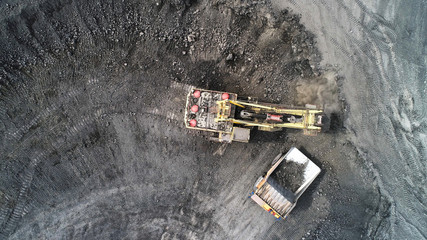 Cable excavator loads overburden from the body of a mining truck.