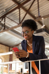 Dark-skinned woman with bright lips holding her smartphone