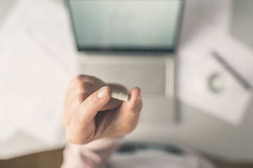 Top view. Tired business woman  holding a headache pill on the workplace with glass of water on the background of graphics and charts printed on the paper.