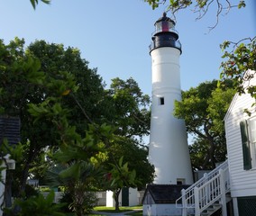 Wide shot of the Key West lighthouse with part of the keeper's quarters in view. The lighthouse is a historical attraction in Key West, Florida.