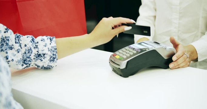 Female customer paying with credit card at clothing store, using credit card, banking services