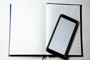 Smartphone and blue notebook on a white background with place for text flatlay