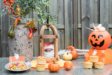 Halloween decorations and food. Pumpkins, vase, flowers and orange cake.