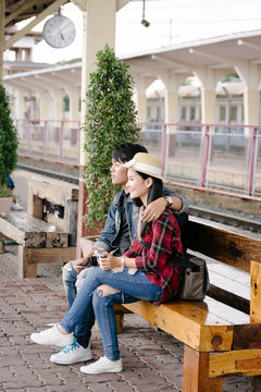 Couple of travel photographer enjoys taking photo during their trip at railway station. Asian  travelers with camera having fun making pictures while waiting for train.