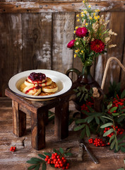Still life with a beautiful bouquet of last summer flowers, pancakes and rowan
