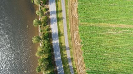 Aerial top down view of country road. Drone shot over fields, trees and lake. © raland