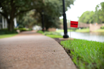 Electrical power line stake flag buried underground utility beside a footpath
