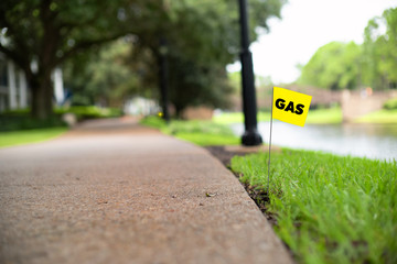 Gas line stake flag buried underground utility beside a footpath