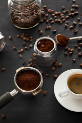 Obraz na płótnie Canvas Geyser coffee maker near cup of coffee, portafilter, spoon and glass jar on dark wooden surface with coffee beans