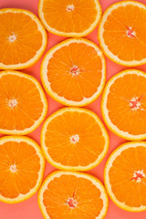 Background of sliced ripe oranges on a pink background vertical.