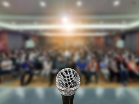 Microphone over the Abstract blurred photo of conference hall or seminar room with attendee background,Small Business training concept,Public speaking