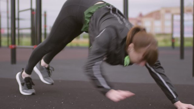 Caucasian woman in sportswear doing plank toe touch exercise at outdoor fitness court