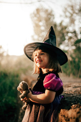 Smiling girl disguised as a witch in the woods during Halloween