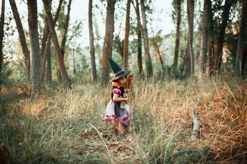 Fototapeta na wymiar Girl standing disguised as a witch in the woods during Halloween