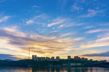 Evening city of Krasnoyarsk on the banks of the Yenisei river at sunset. Beautiful view. Buildings of the new neighborhood. Beautiful sky.